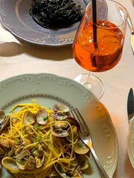 View of table set with plates of pasta dishes and cocktail Stock Photos
