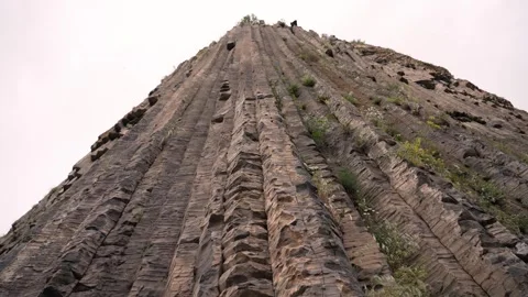 View of tall rock formation with plants in cloudy sky. Stock Footage 341675668