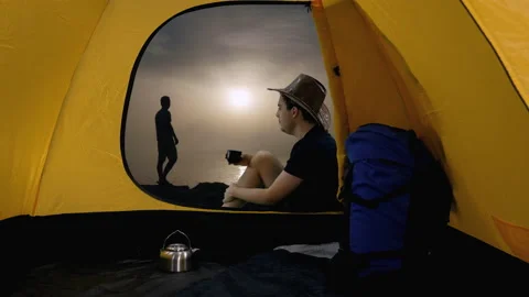 View from tent hiker sits drinking tea stranger coming up at seascape background Video stock 161020556