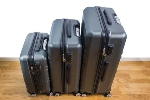 View of three different size suitcases standing on parquet floor in room. Stock Photos