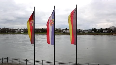 View at three flags slowly waving in a breeze in front of the river Rhine Stock Footage 236697828
