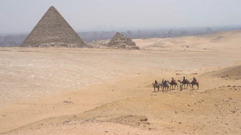 View of the three pyramids of Giza with camel caravan, Giza, Egypt Video stock 116336479