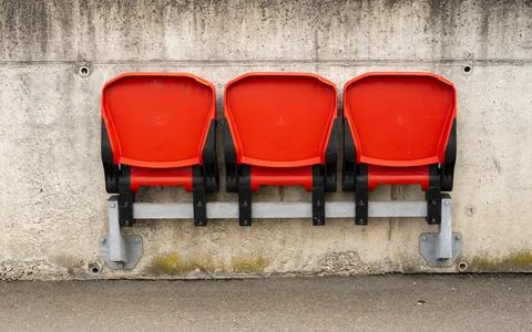 View of three red folding chairs attached to the wall at a public transport s Stock Photos