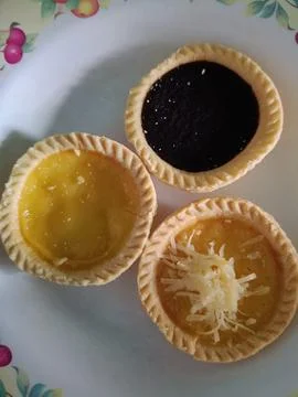 View of three variants of egg tarts on a plate Stock Photos