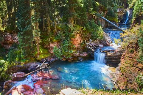 View of three waterfalls going through canyon with red rocks and pine trees Stock-Fotos
