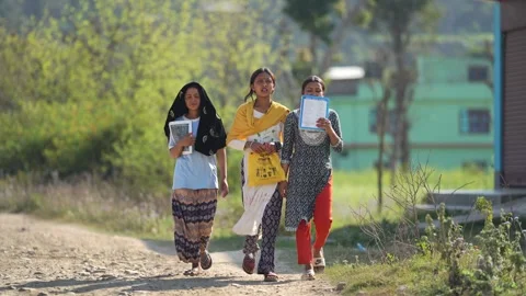View of three young female students walking along a dirt road, Nepal. Video stock 335476438