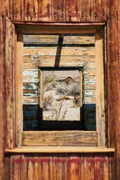 View through abandoned ghost town train with desert structure in window Stock Photos