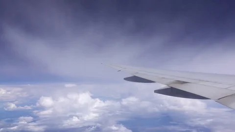 View through aircraft window on beautiful cloudscape and airplane wing in 4K Видео 75930728