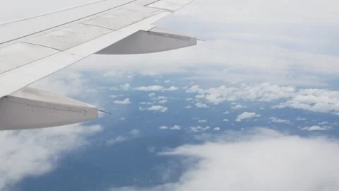 View through aircraft window with plane's wing over blue sky Stock Footage 283629999