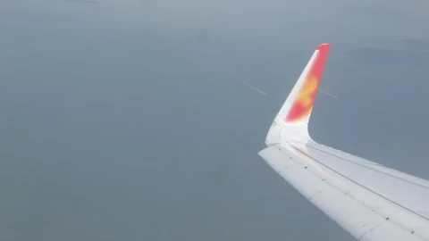 View through aircraft window with plane's wing over blue sky with foggy smo.. Stock Footage 338332186