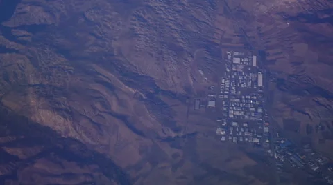 View through an airplane window above the mountains in the blue sky in clouds Video stock 68769854