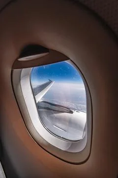 View through airplane window during flight on a Sunny day with cloudy sky Stock Photos