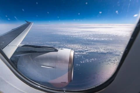 View through airplane window during flight on a Sunny day with cloudy sky Stock Photos