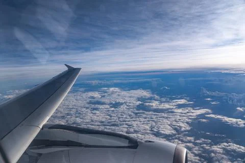 View through airplane window during flight on a Sunny day with cloudy sky Stock Photos