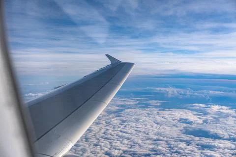 View through airplane window during flight on a Sunny day with cloudy sky Stock Photos