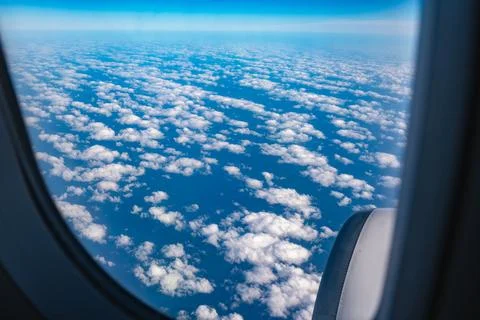 View through airplane window during flight on a Sunny day with cloudy sky Stock Photos