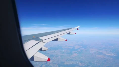 A view through an airplane window, showing the wing and the landscape below.. Stock-Footage 282714897