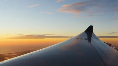View through airplane window of wing and sunrise Stock Footage 132188886