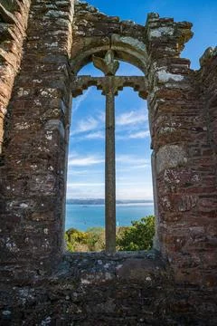 View through ancient stone window ruin at Mount Edgcumbe towards blue sea Stock Photos