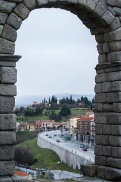 A view through the arch of famous ancient roman aqueduct of Segovia to town.. Stock-Fotos