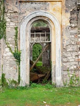 View through the arched doorway of a window. Abandoned littered overgrown Stock Photos