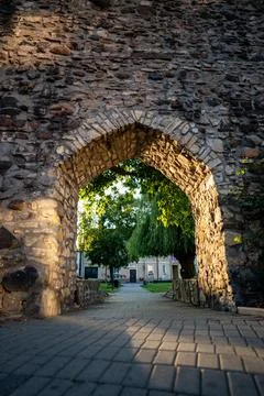 View through an arched passage in a stone wall into a city park at sunset Foto stock