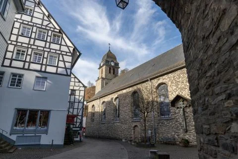 View through an archway at a half-timbered house and church in Monschau Stock Photos