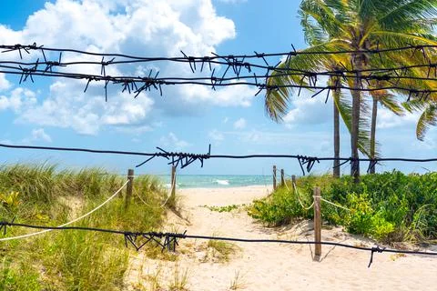 View through the barbed wire to Sand Path going to the ocean in Miami Beach Stock Photos