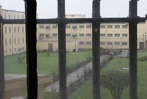 View through a barred window of rainy prison yard and buildings Stock Footage 86919803