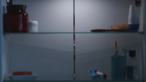 View Through Bathroom Cabinet Of Frustrated Young Man Running Out Of Toothpaste Stock Footage 124579241