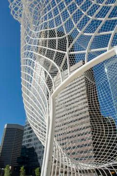 View through big mesh head public art display in front of office tower Stock Photos