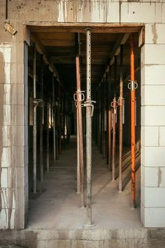 View through a block doorway of adjustable metal shoring jacks holding up a.. Stock Photos
