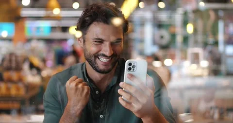 View through a cafe window to handsome young Hispanic man with smartphone Stock Footage 218565521