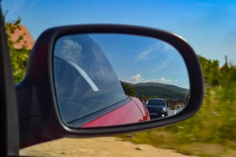 View Through Car Side Mirror Reflecting Rolling Hills and Blue Sky Stock Photos