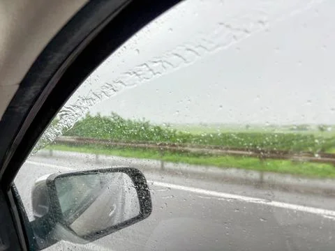 View through a car window during rainy weather with water droplets on glass Stock Photos