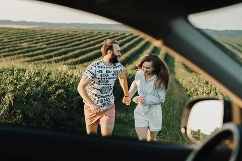 View through car window, happy middle-aged couple running in the beautiful Stock Photos