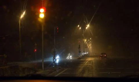 View through car windshield to night road with moving cars. Stock Photos