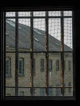 View through cell window in a jail with rusty iron bars to the old prison Stock Photos