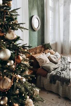 View through a Christmas tree at a large double bed with wooden headboard in a Stock Photos