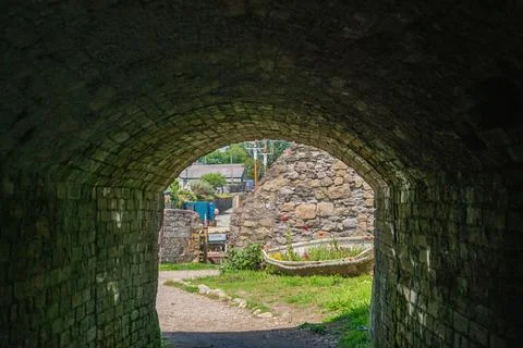 View Through Dark Stone Archway Towards Brightly Lit Coastal Village Scene Stock Photos