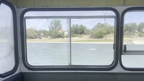 View Through Ferry Window Across a Peaceful Riverside Village Landscape Vídeos de archivo 342028062