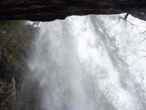 View through the flow of the waterfall from the inside. Motion blur Stock Photos