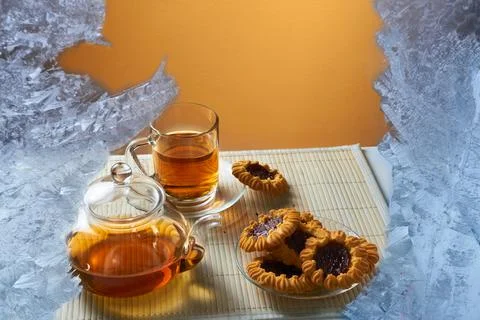View through the frozen window on the table with warm tea and cookies Stock Photos