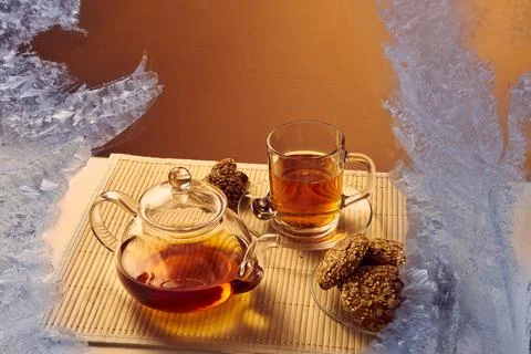 View through the frozen window on the table with warm tea and cookies Stock Photos