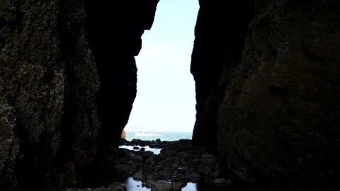 View through gap in the cliff of tourist boat sailing past 库存影片 145875962