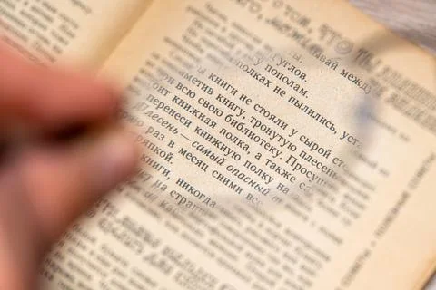 View through glasses in hand on a text in the book Stock Photos