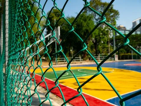 View through green chain link fence of colorful outdoor basketball court wi.. 스톡 사진