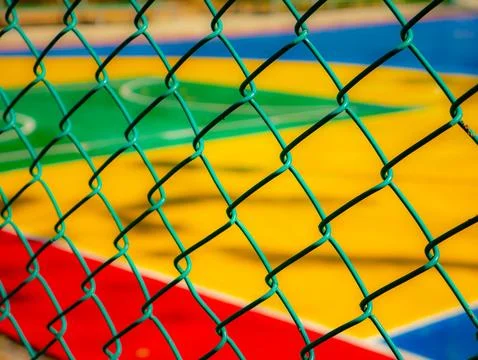View through green chain link fence of colorful outdoor basketball court wi.. Stock Photos