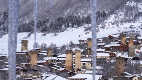 View through hanging icicles of the snow-covered village of Mestia in the C.. Vídeos de archivo 342130506