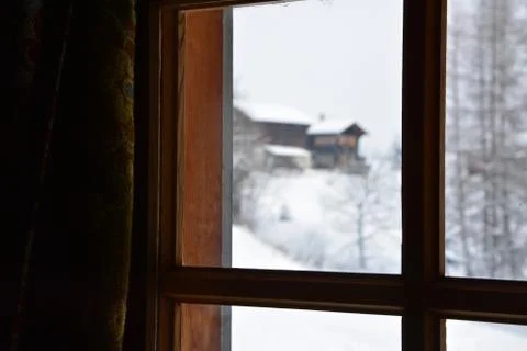 View through a hut window with winter, snow ad some huts outside Fotos de archivo